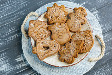 Homemade gingerbread cookies on tray on grunge gray wooden background. Christmas and New Year celebration background. Close up of home baked cookies with icing.