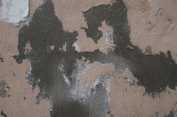 Photo of the destroyed surface of the exterior wall. Cracks, plaster failures, paint scuffs. In gray, brown colors.