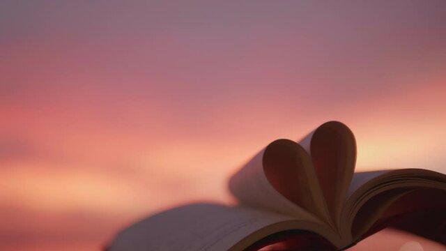 Heart from a book page against a beautiful sunset and leave space for adding your content.
