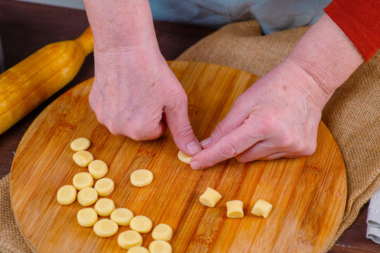 Hands of an elderly woman work with pieces of dest, making blanks for dumplings