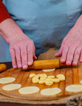 Hands of an elderly woman work with pieces of dest, making blanks for dumplings