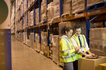 Fototapeta premium Worker and manager meeting at laptop in aisle of distribution warehouse