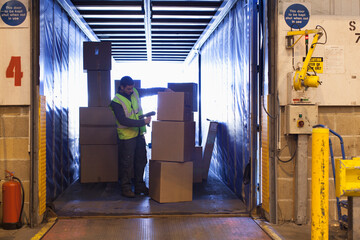 Male worker scanning boxes in truck at warehouse loading dock © Martin Barraud/Caia Image