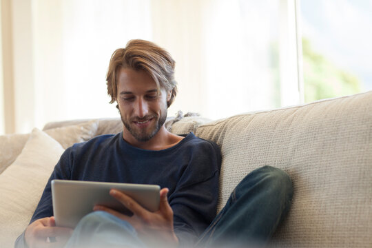 Smiling young man using digital tablet on sofa