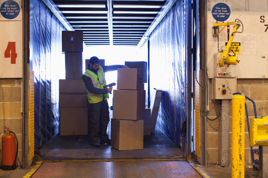 Male worker scanning boxes in truck at warehouse loading dock