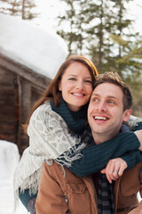 Fototapeta premium Portrait happy affectionate couple hugging outside snowy cabin