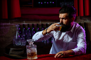 Man with beard and mustache holds alcoholic beverage on bar background. Service and alcoholism concept.