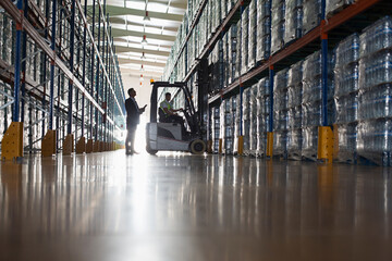 Male supervisor and worker operating forklift in distribution warehouse © Martin Barraud/Caia Image