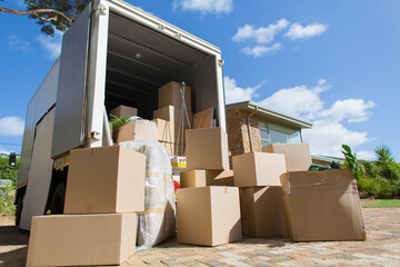 Cardboard boxes outside moving van and house in sunny driveway © Paul Bradbury/Caia Image