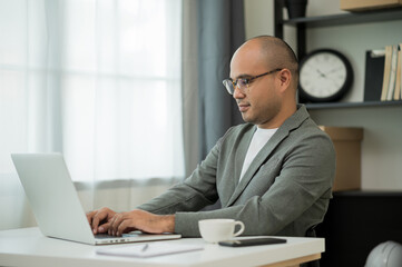 A middle-aged man around the age of 35. Working at home Work through the laptop. He was wearing a...