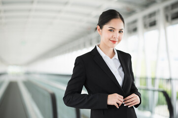 Young asian business woman standing and smile. Beautiful female in black suited.