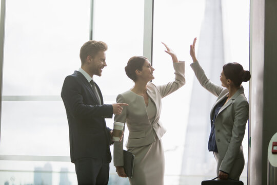 Corporate business people high-fiving in office window