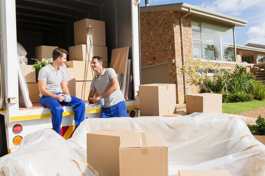 Male movers enjoying coffee break at back of moving van