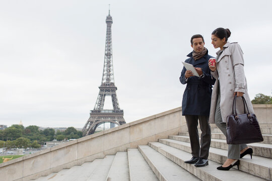 Business people using digital tablet on stairs, Eiffel Tower, Paris