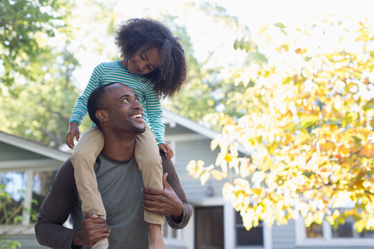 Happy father carrying daughter on shoulders