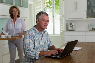 Fototapeta premium Senior couple using laptop in kitchen