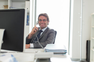 Fototapeta premium Portrait confident businessman talking on telephone at computer