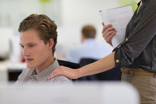 Businesswoman touching businessman on shoulder