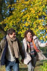 Fototapeta premium Playful young couple running in autumn park