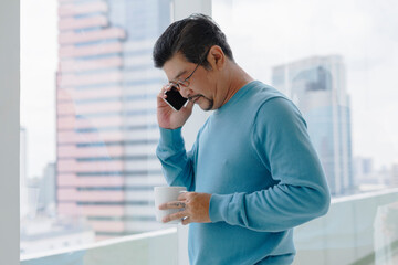 Senior man in blue long sleeve shirt wearing eyeglasses talking on the phone.