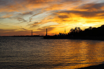 Sunset in city Toronto. Darkness cityscape and golden hour.  Blue and yellow colors cloudy sky and lake Ontario