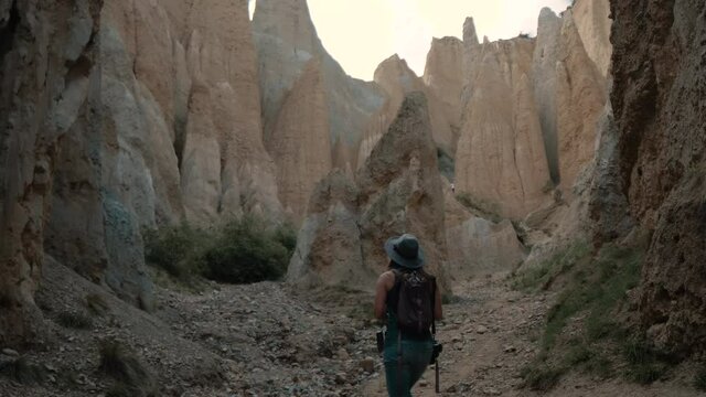 Woman hiker taking pictures among clay cliffs mountains
