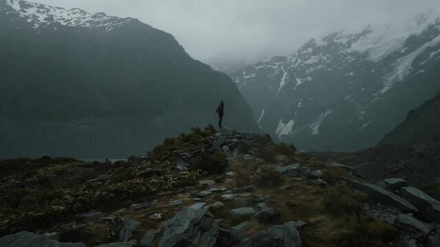 Hiker standing, looking at the cold large mountains around her
