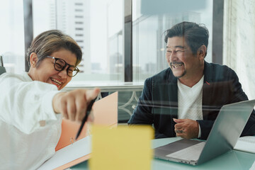 Senior business people pointing at sticky note.