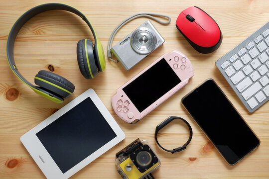Smartphone with portable game consoles and ebook reader and other electronic gadgets on wooden background.Top view.