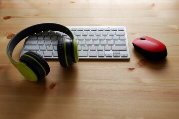 White keyboard with wireless mouse and bluetooth wireless headphones on wooden background.Top view....