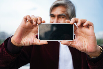 Senior man holding smartphone for mock up.