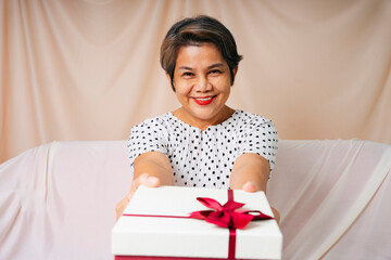 Cool old elderly senior woman in white polka dot dress with birthday gift box.