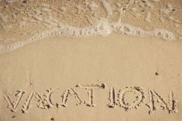 Inscription vacation and sea wave on sand at beach. Summer time