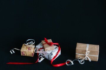 gift boxes Packed in wrapping paper and tied with ribbons for the new year or Christmas lie in a pile on a black background