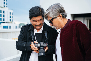 Senior photographer and old man take a look at picture in camera.