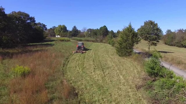 An aerial of a farmer cutting his pasture with a brush hog mower