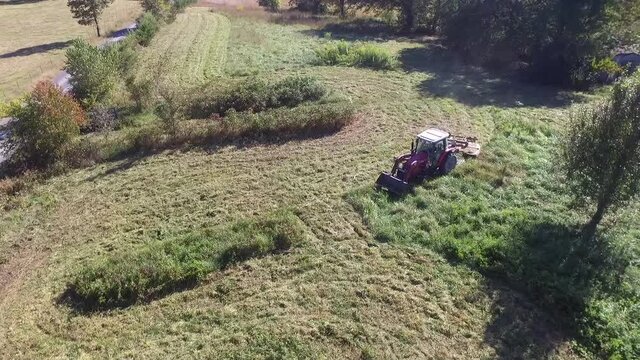 Aerial footage of a farmer brush hogging his pasture grass with a large mower