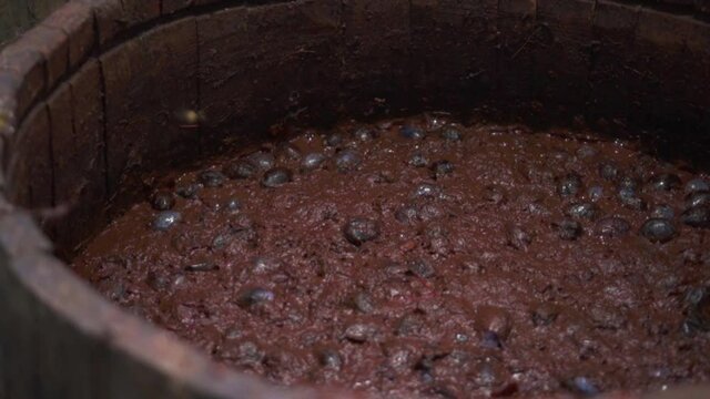 Marc fruit ferment from plums - mix material in barrel for alcohol distillation