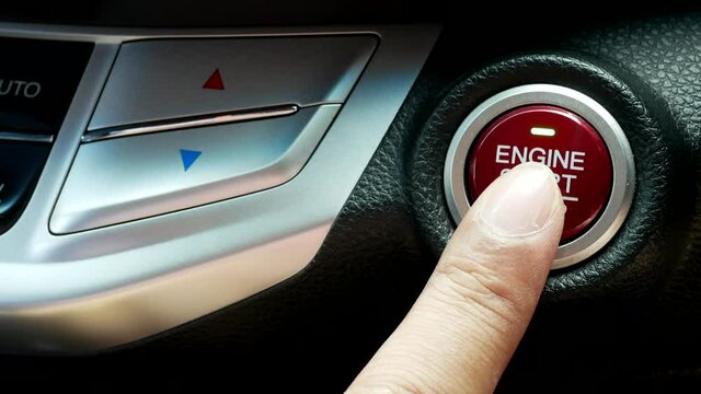 finger pressing on button to start stop engine of car.
