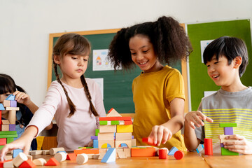 Group of multiethnic school friends using toy blocks in classroom, education, learning, teamwork. Children playing with wooden blocks in classroom - 383200534