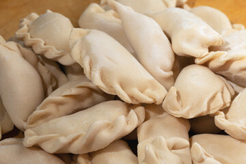 raw frozen dumplings on wooden background as grocery pattern