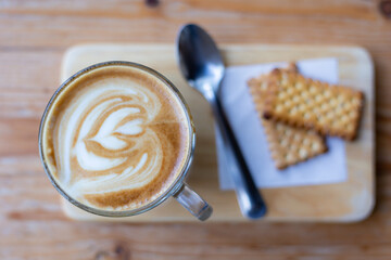 latte coffee with white heart cream and topping on the brown wood texture taken by top view photography.