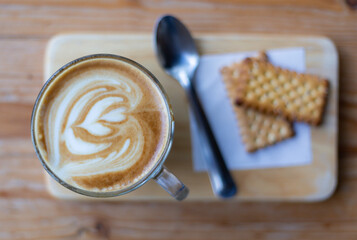 latte coffee with white heart cream and topping on the brown wood texture taken by top view photography.