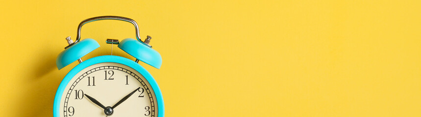Alarm clock on yellow background, banner. Front view. Copy space.