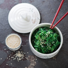 Bowl of chuka salad topped with sesame, high angle view on a brown stone background, studio shot