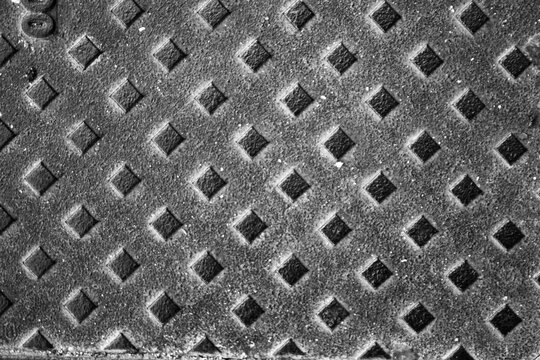 evocative black and white texture image of metal plate with embossed rhombus pattern