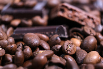 Close-up of dark roasted coffee beans and chocolate background.