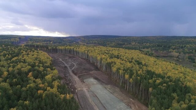 Construction of a new road in the forest area. Aerial view construction road place. Construction machinery for the construction of a road in the forest. Scale of deforestation from a bird&rsquo;s eye, a wid