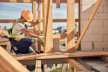 Serious worker measuring distance before fastening screws