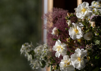 bouquet of roses and field flowers in a vase on the table close-up